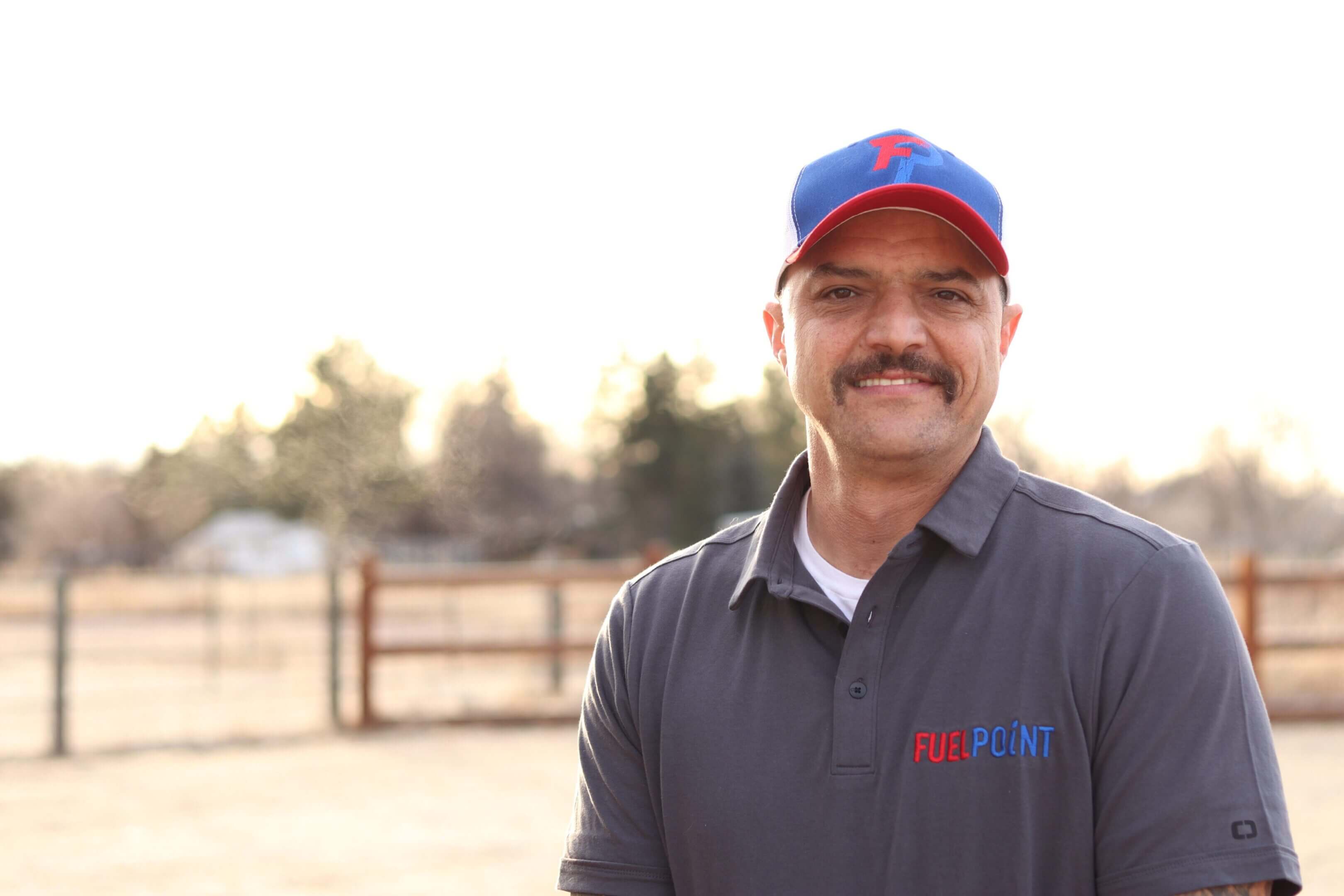 Man smiling outdoors in a cap.